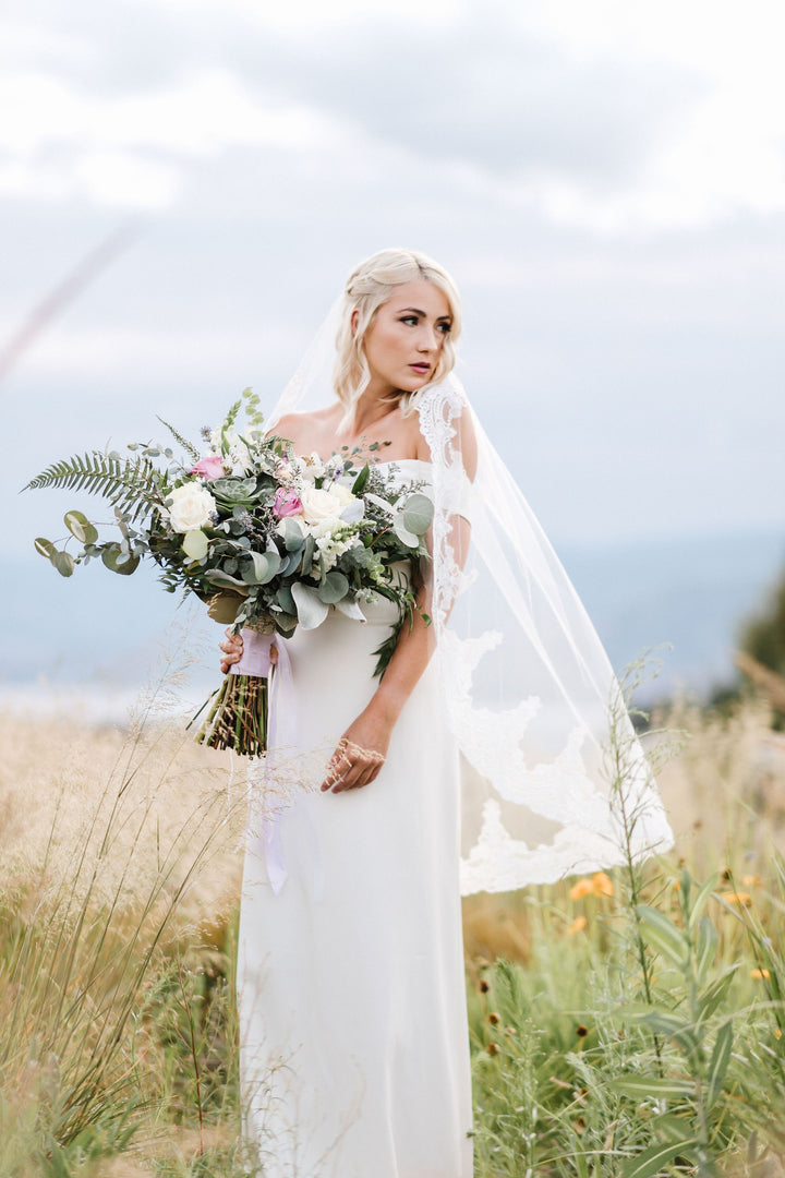 Vintage-inspired lace wedding veil flowing in natural setting