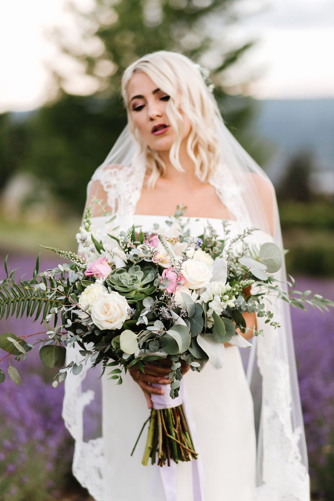 Bride wearing CASSANDRA lace veil outdoors with bouquet