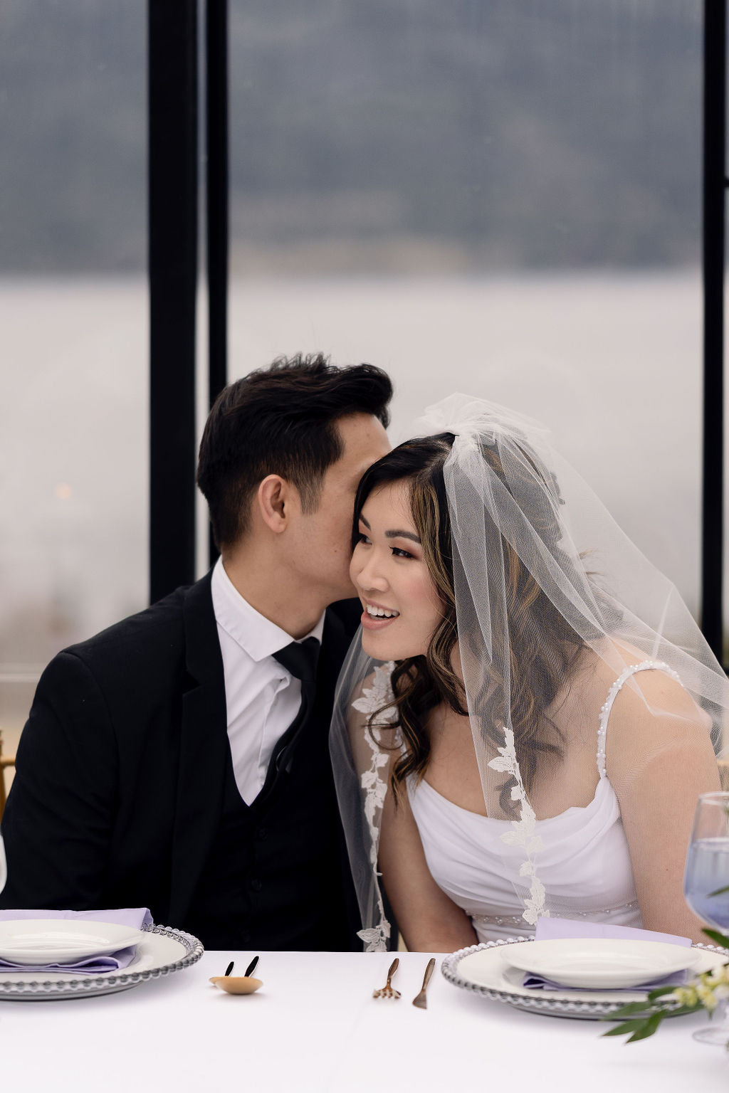 Close-up of EVERLY fingertip wedding veil with soft tulle and lace trim, bride smiling at reception, romantic bridal veil styling, Kelowna wedding